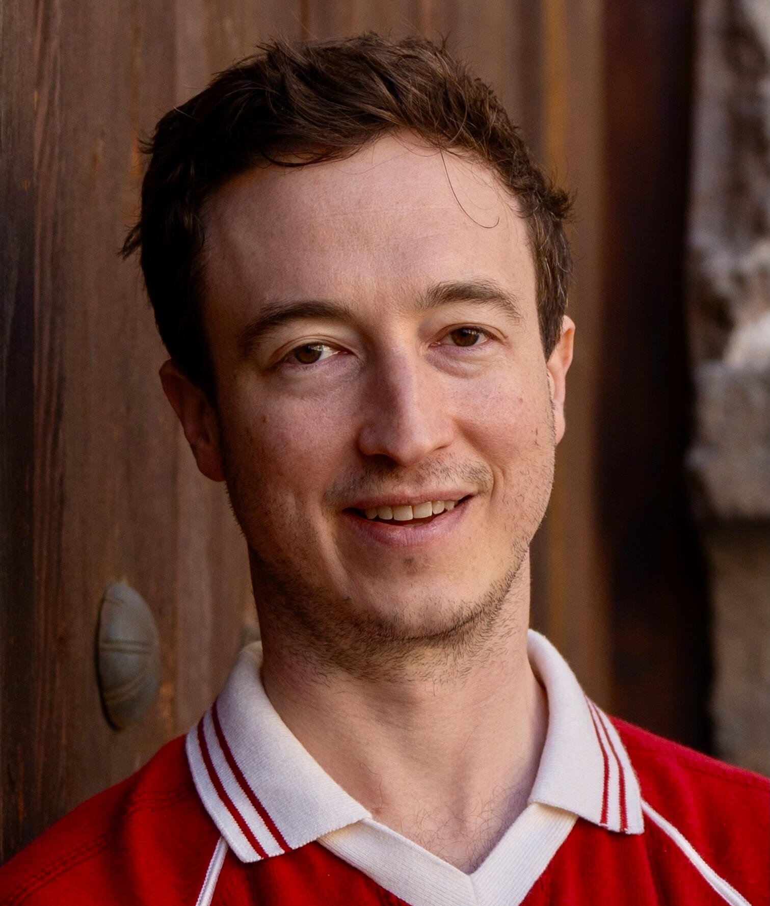 Liam Lindner smiling in a wood doorway.